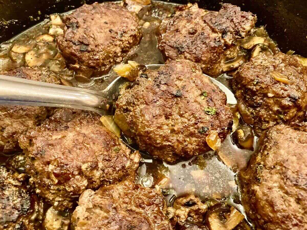 Spooning gluten-free Salisbury Steak out of skillet