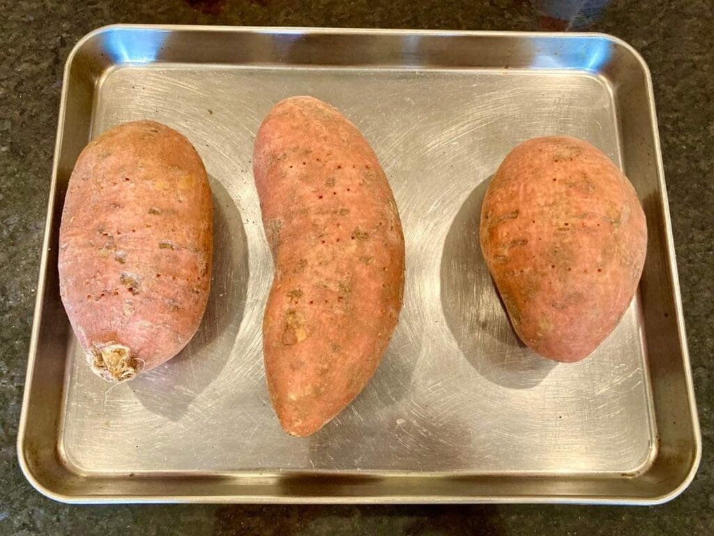 3 sweet potatoes on baking sheet