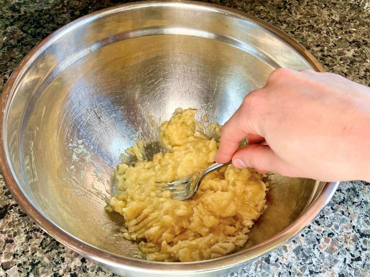 Mashing bananas with a fork in a bowl.