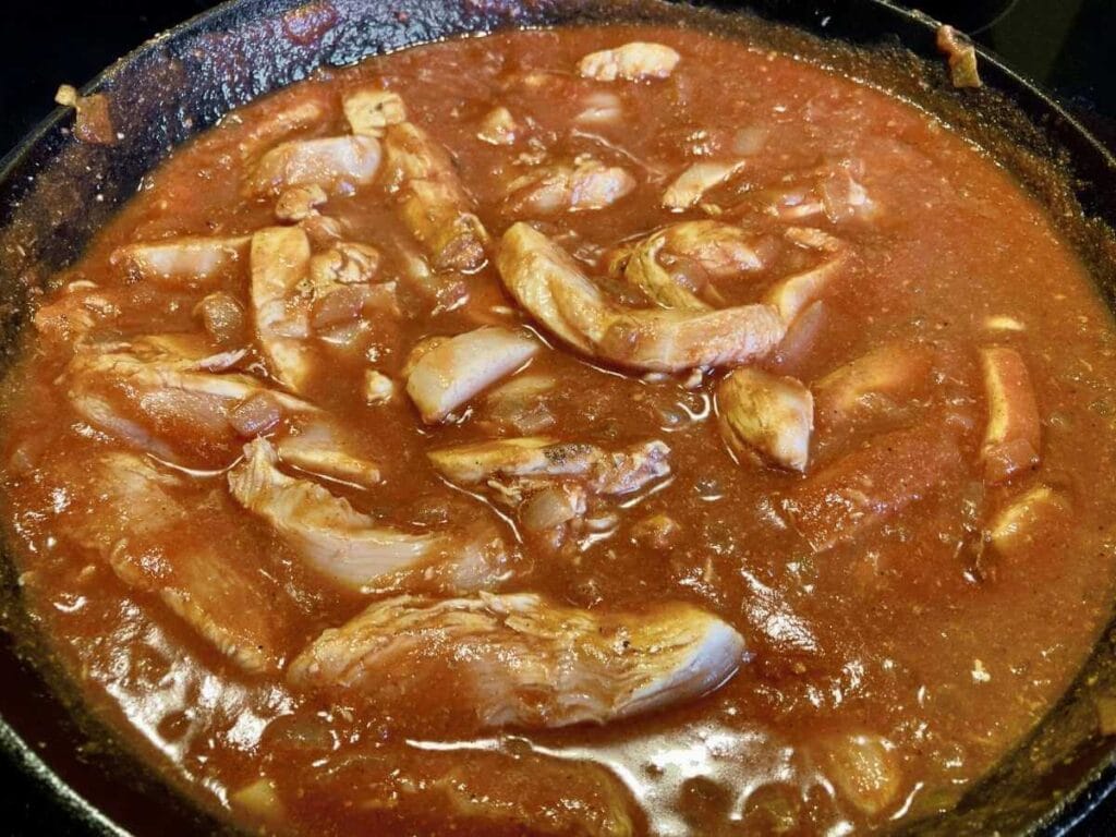 Chicken cooking in tomato sauce.