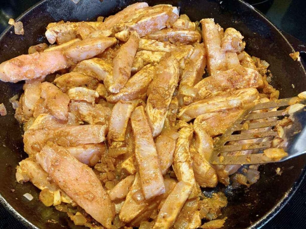 Chicken strips in a skillet.