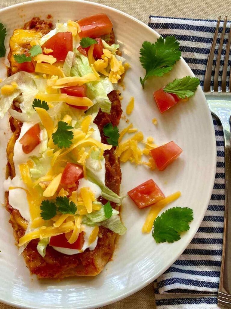 Chicken and cilantro enchilada on a plate with a fork.