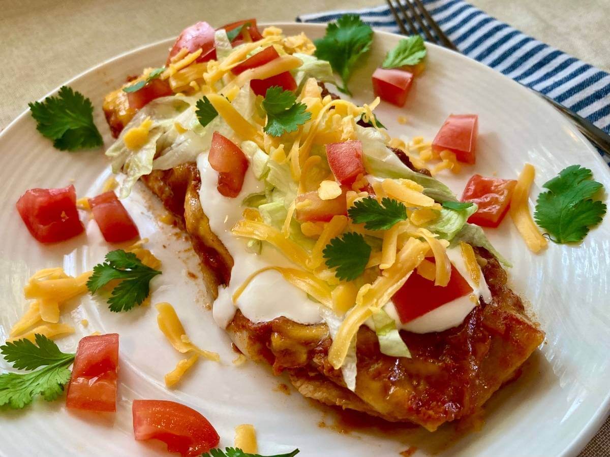 Angle view of chicken and cilantro enchilada on a plate.