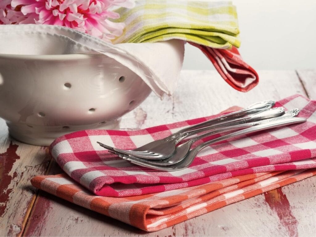 Cloth napkins in a bowl and a stack of them with forks.