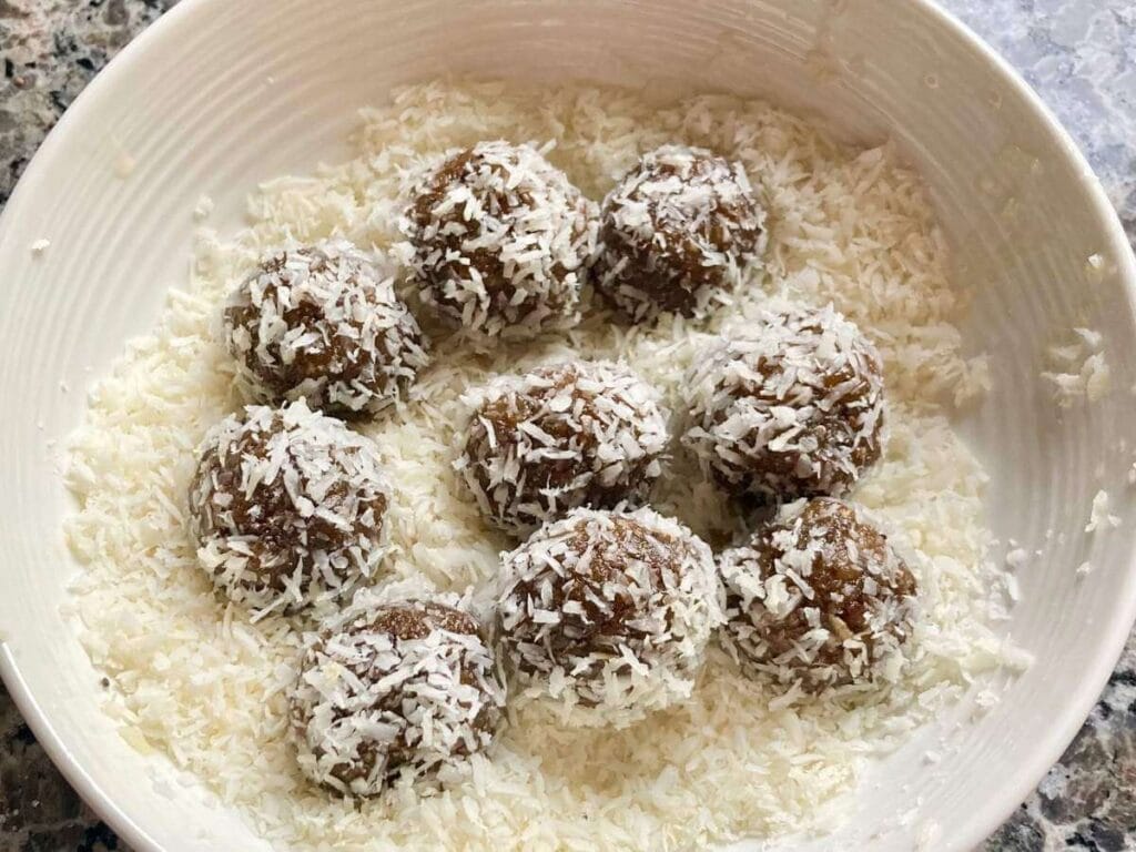 Rolling energy balls with dates in coconut.