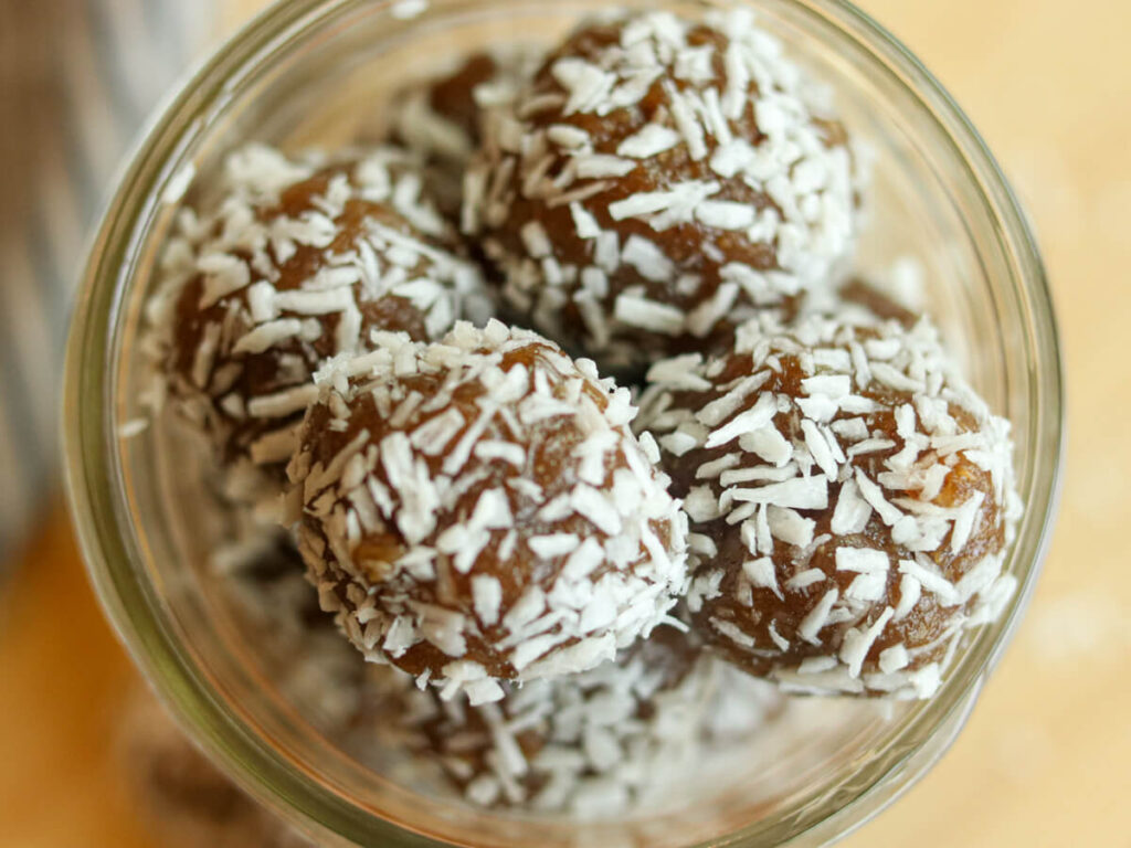 Top view of a glass jar heaped full of energy balls.