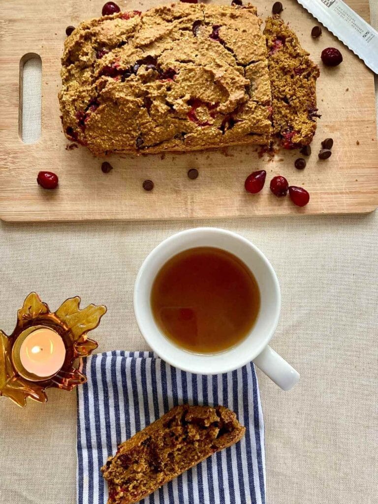 Pumpkin cranberry bread on a cutting board and slice on a napkin.