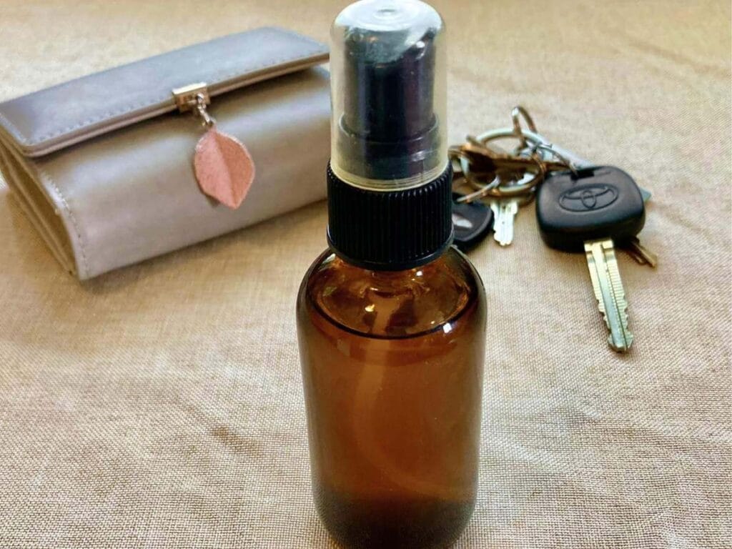 Bottle of hand sanitizer spray with keys and a wallet.