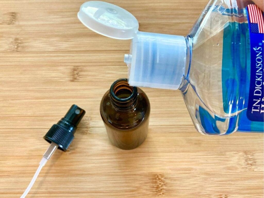Pouring rubbing alcohol into a spray bottle.