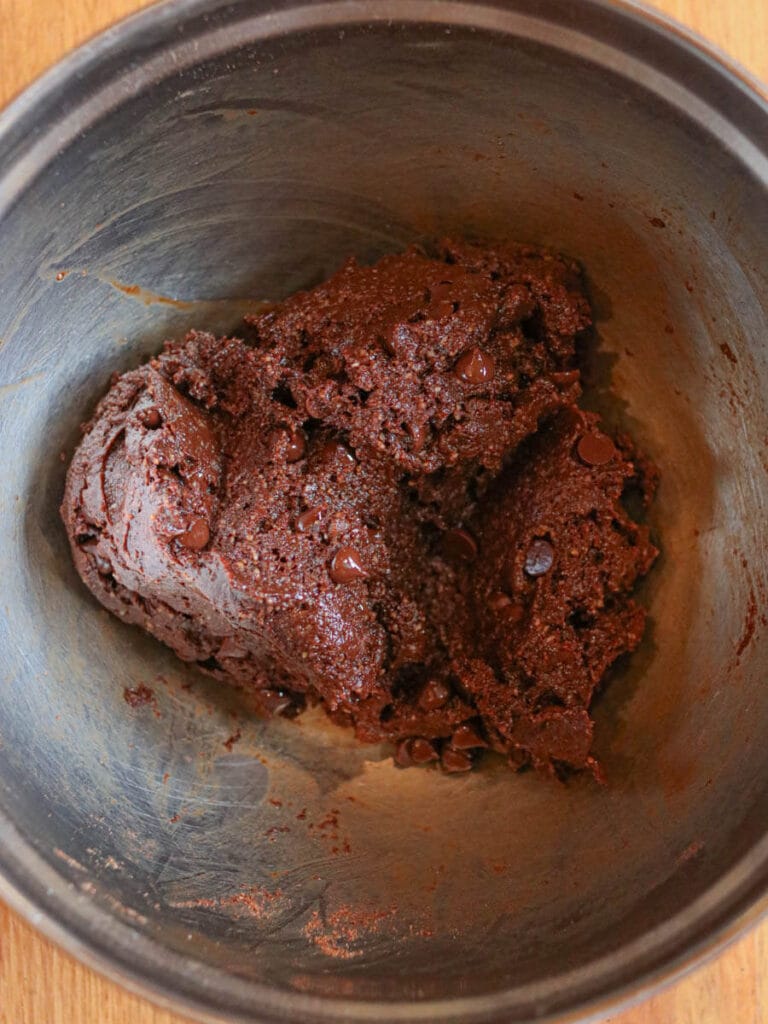 Vegan brownie batter with chocolate chips in a stainless steel bowl.