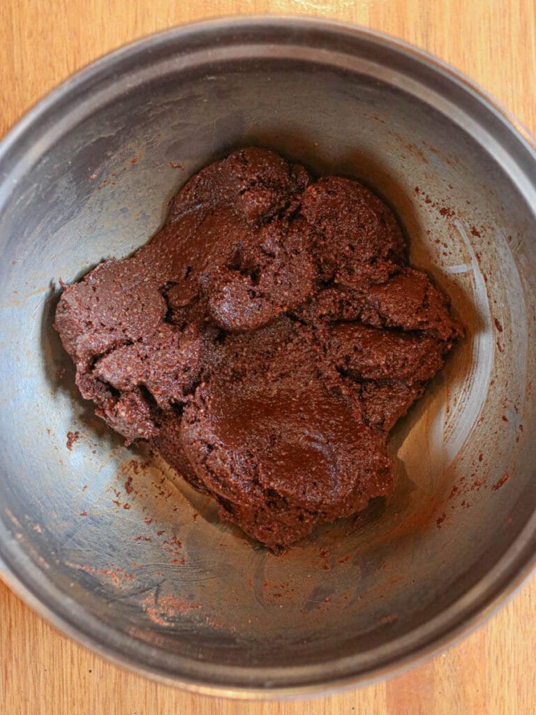 Wet and dry brownie ingredients mixed together in a stainless steel bowl.