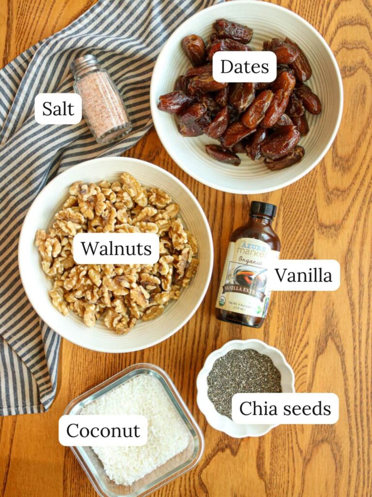Labeled ingredients on a table including dates, salt, walnuts, vanilla, coconut, and chia seeds.