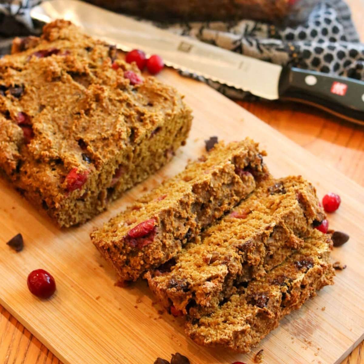 Close-up view of a partially sliced loaf of gluten-free pumpkin bread on a cutting board.