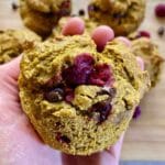 Hand holding pumpkin cranberry muffin.