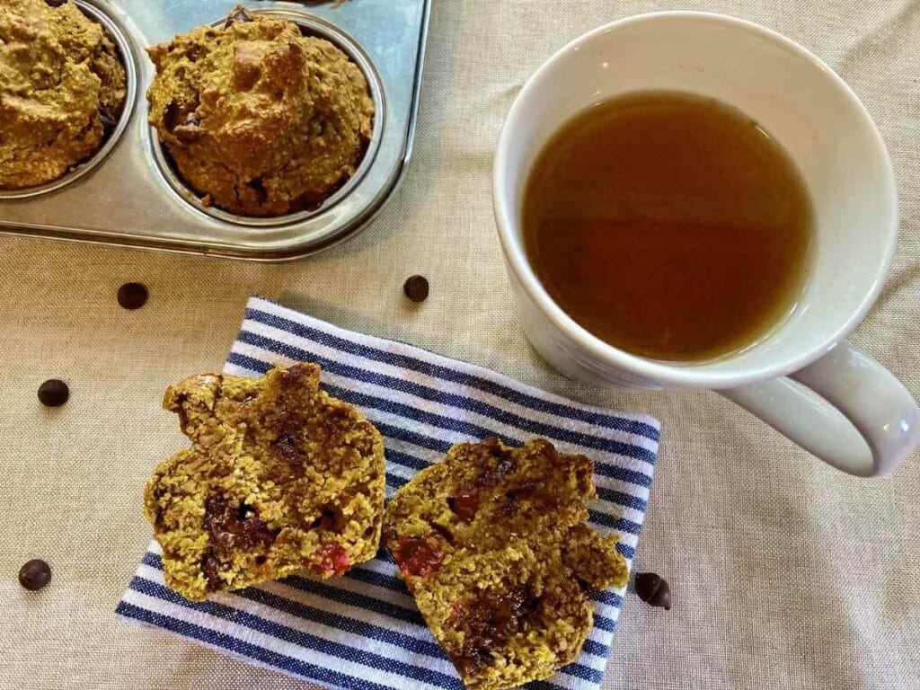 Pumpkin cranberry muffin cut in half on a cloth napkin.