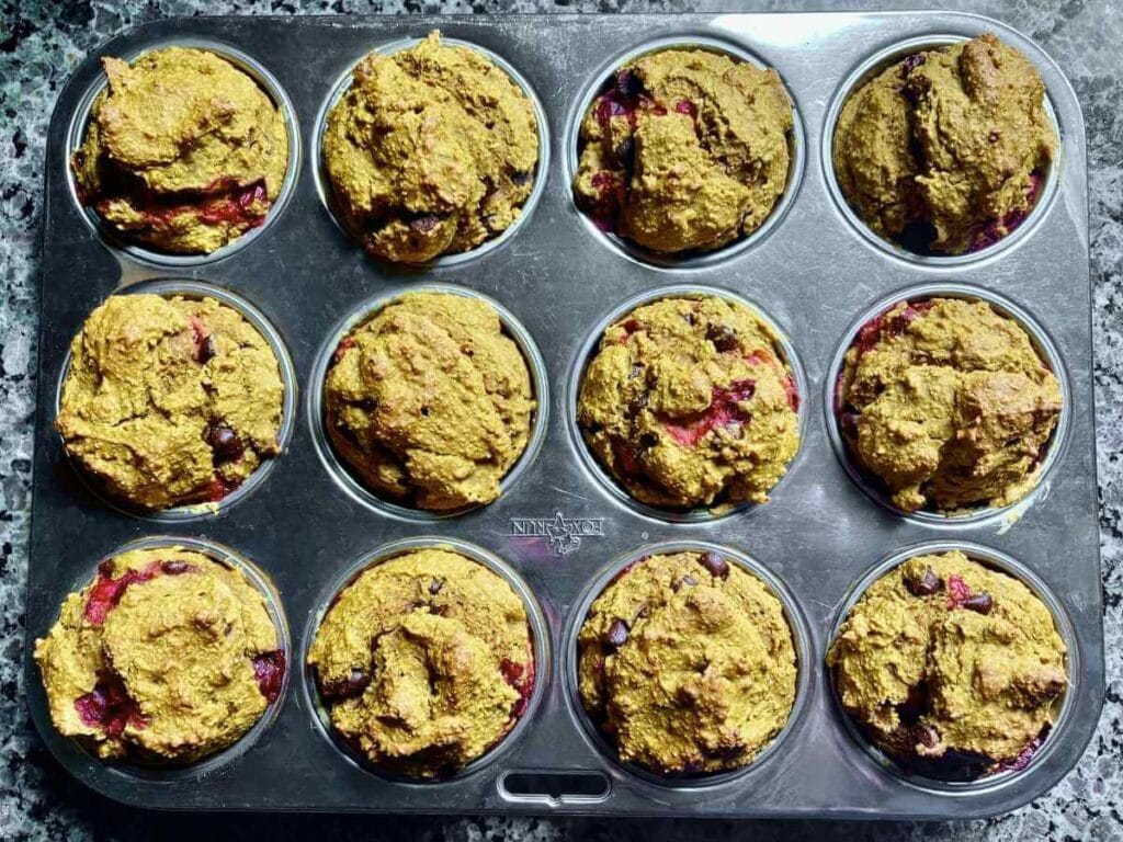 Pumpkin cranberry muffins fresh out of the oven in a muffin pan.