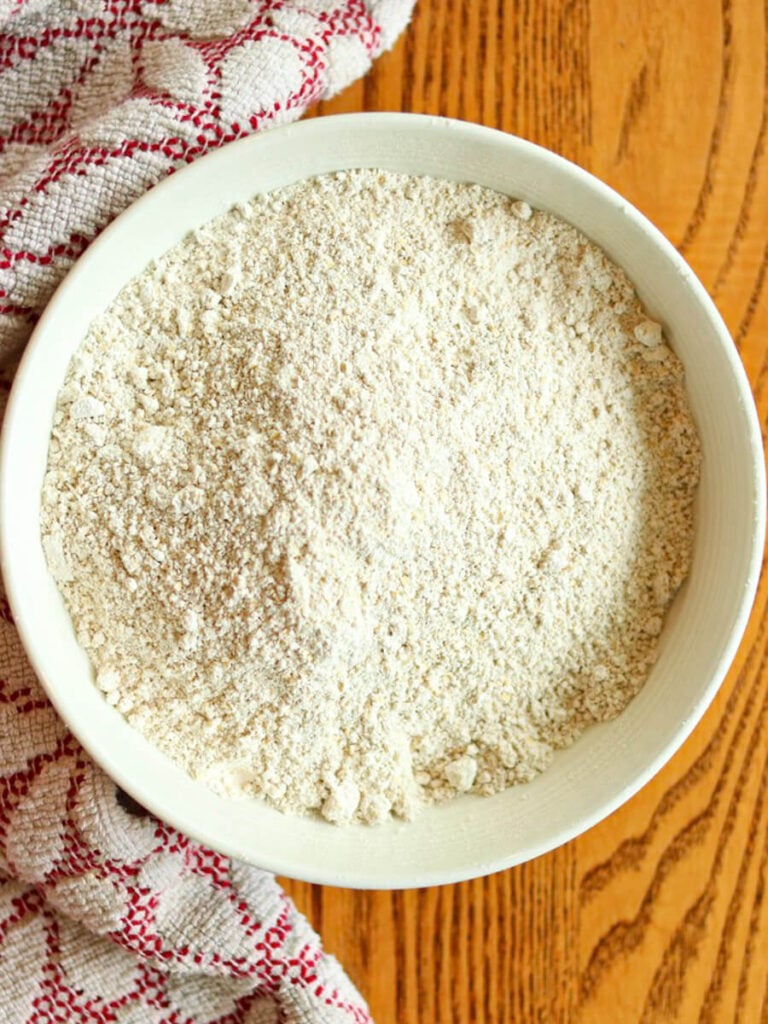 Top view of a bowl of oat flour on a wooden table.