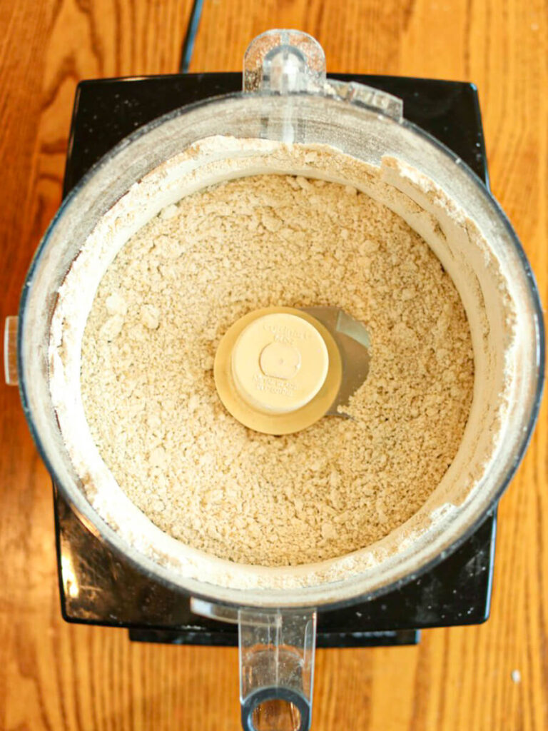 Top view of oats being ground into oat flour in a food processor.