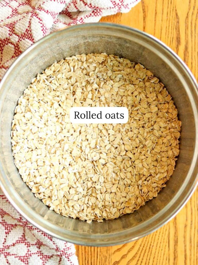 A stainless steel bowl full of oats labeled "rolled oats".