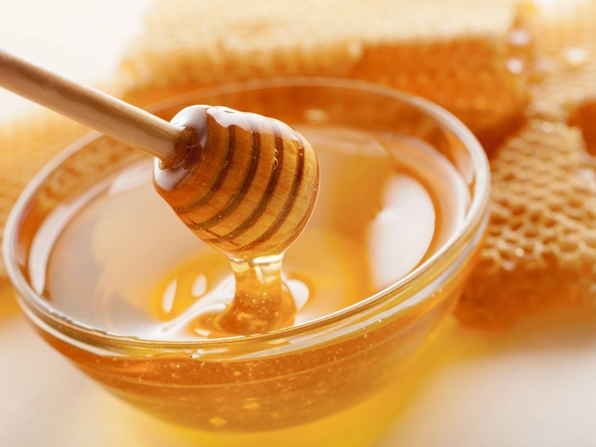 Scooping honey out of a bowl.