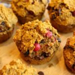 Close-up view of a gluten-free pumpkin muffin on a wooden surface.