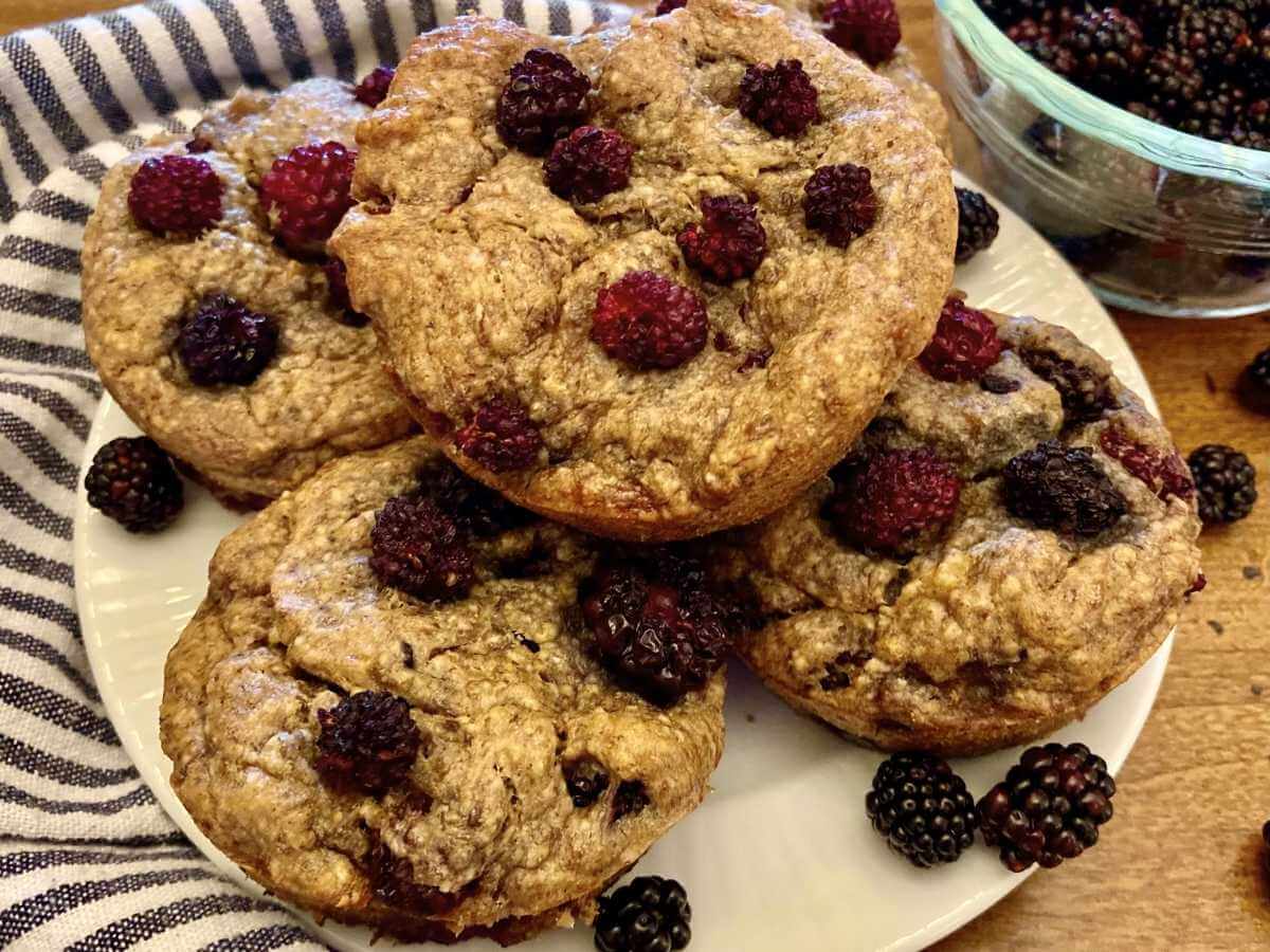 Blackberry banana breakfast muffins stacked on a plate.