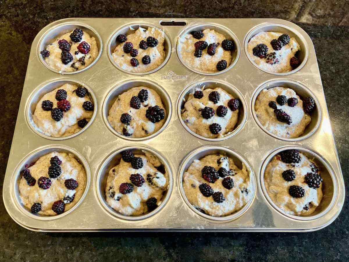 Blackberry banana breakfast muffin batter in a muffin pan.
