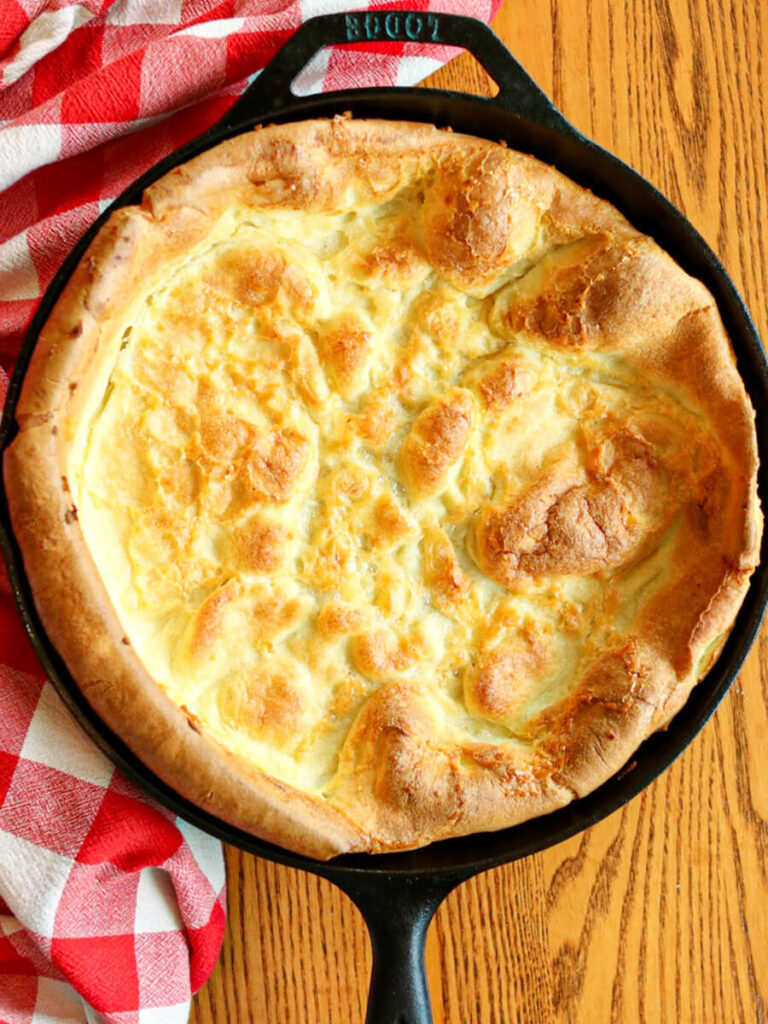 Gluten-free Dutch baby pancake fresh out of the oven on a wooden table.