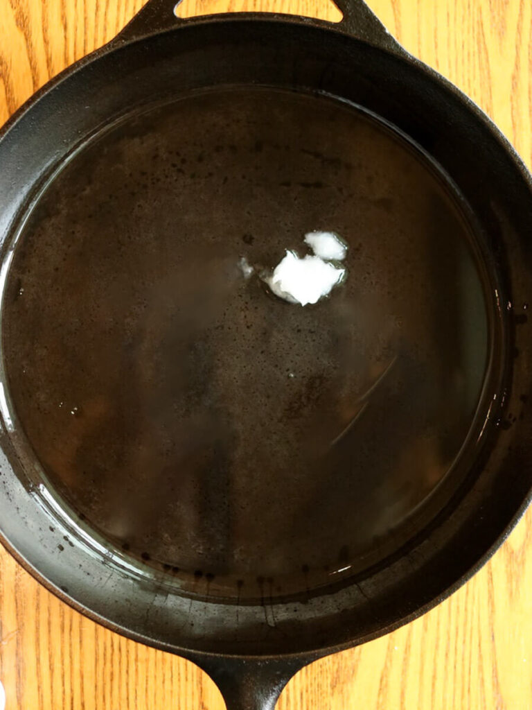 Coconut oil melting in a hot cast iron skillet.
