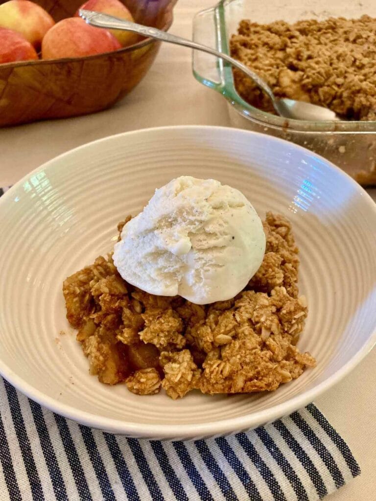 Closeup of apple crisp with ice cream in a bowl.