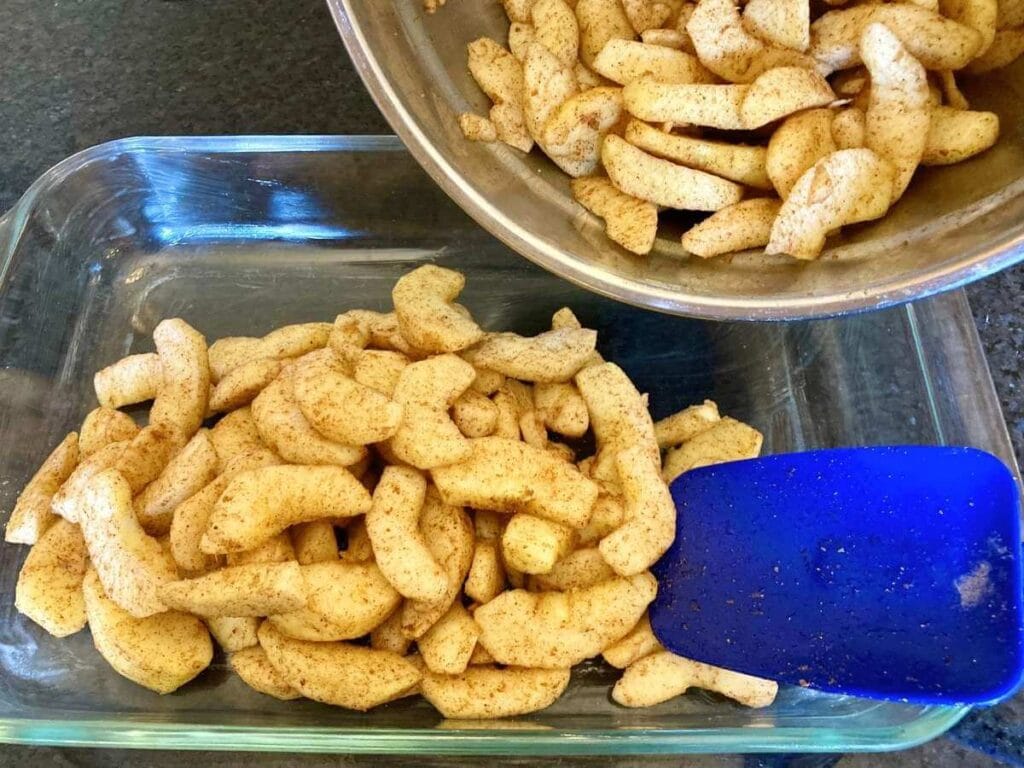 Dumping apple slices into a baking dish.