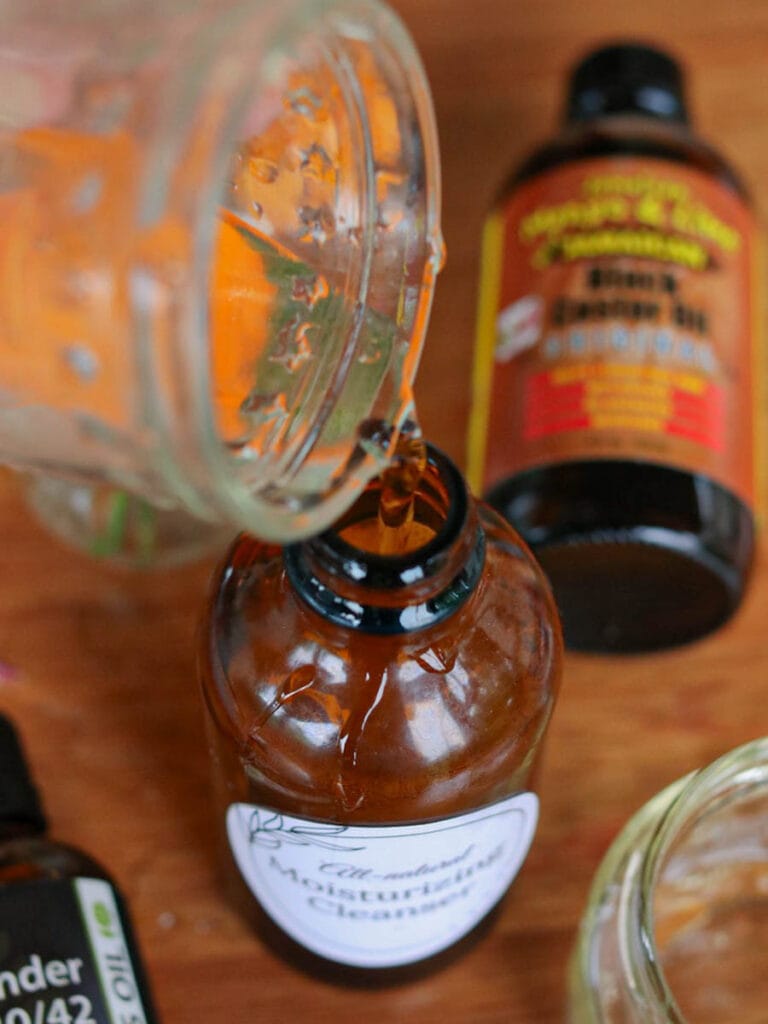 Pouring water into an amber glass spray bottle on a wooden surface.