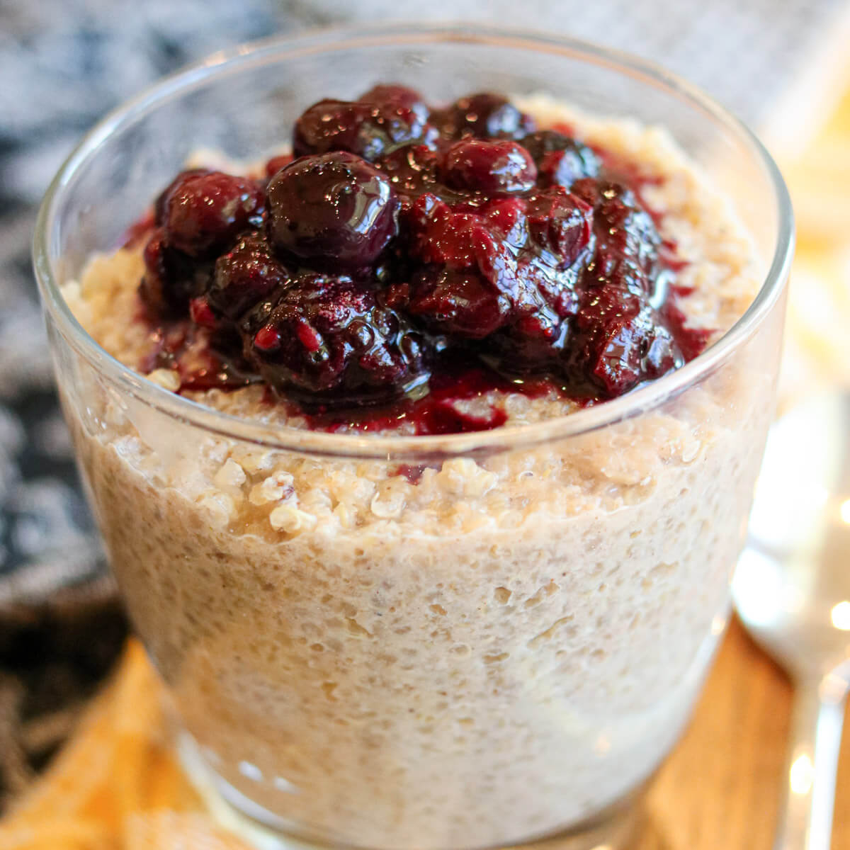 Closeup of quinoa pudding in a glass topped with berry sauce.