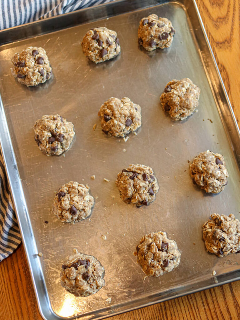 Oatmeal chocolate chip cookies on a cookie sheet on a table.