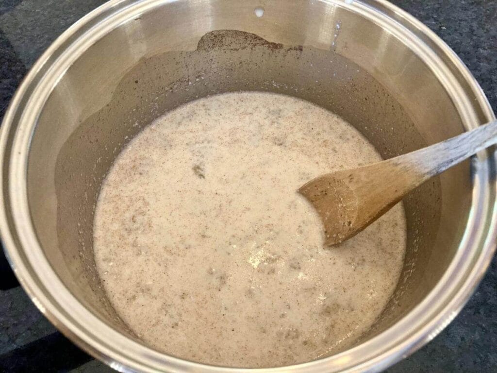 Stirring quinoa pudding ingredients in a pan on the stove.