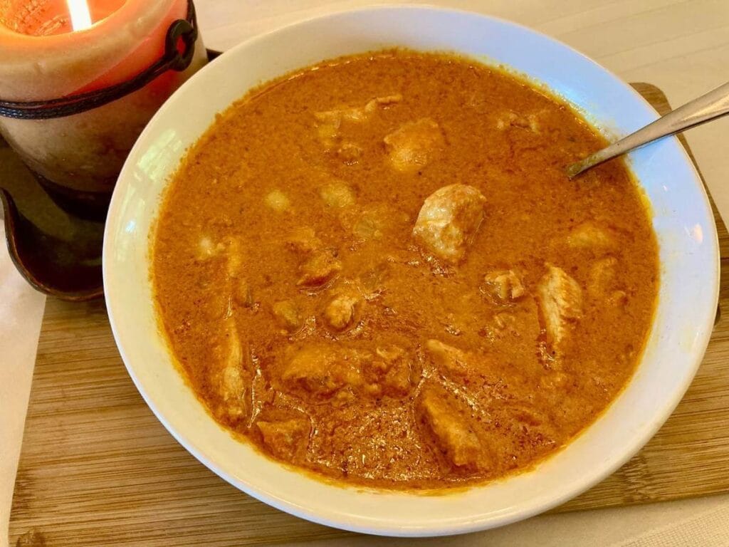 Indian chicken curry in a serving bowl with a spoon.