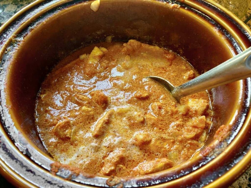 Stirring cream into chicken curry in a slow cooker.