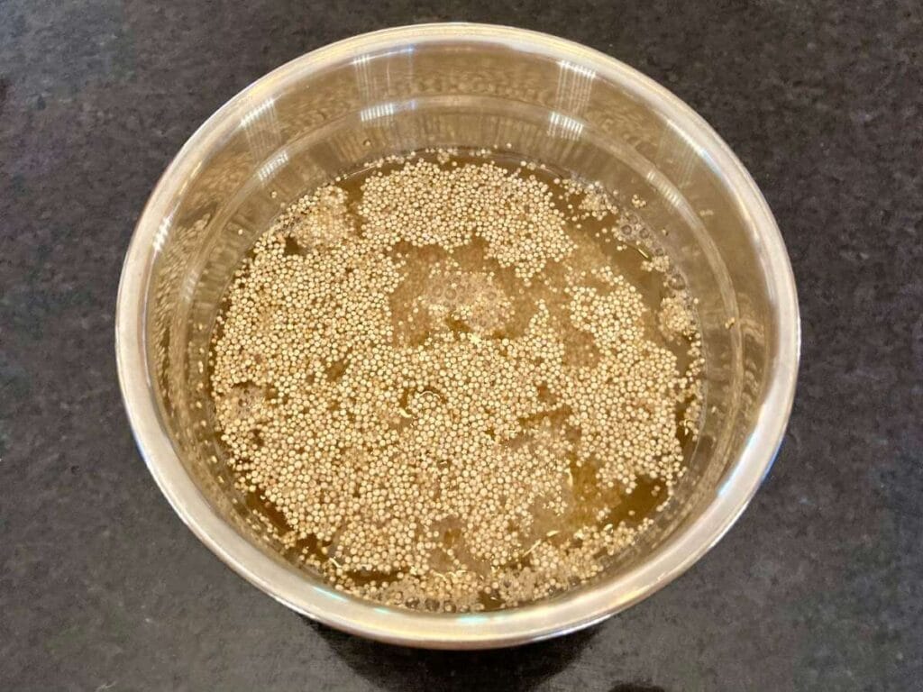 Quinoa soaking in water and vinegar in a bowl.