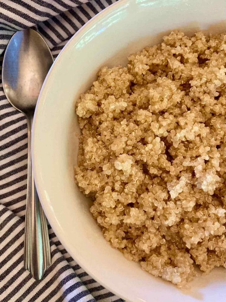 Bowl of cooked soaked quinoa with a spoon beside it.