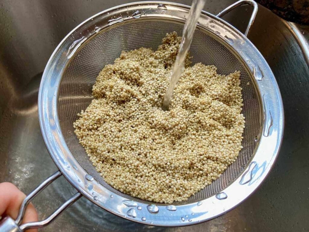 Rinsing quinoa in a mesh strainer.
