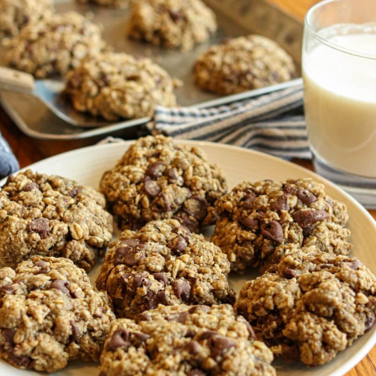 Close up view of oatmeal cookies on a plate with milk in the background.