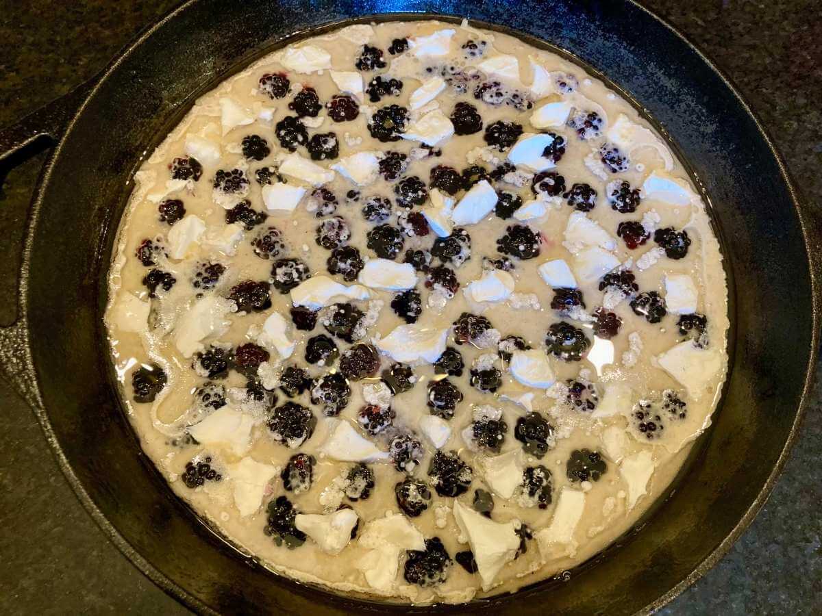 Unbaked blackberry cheesecake German pancakes in a skillet.