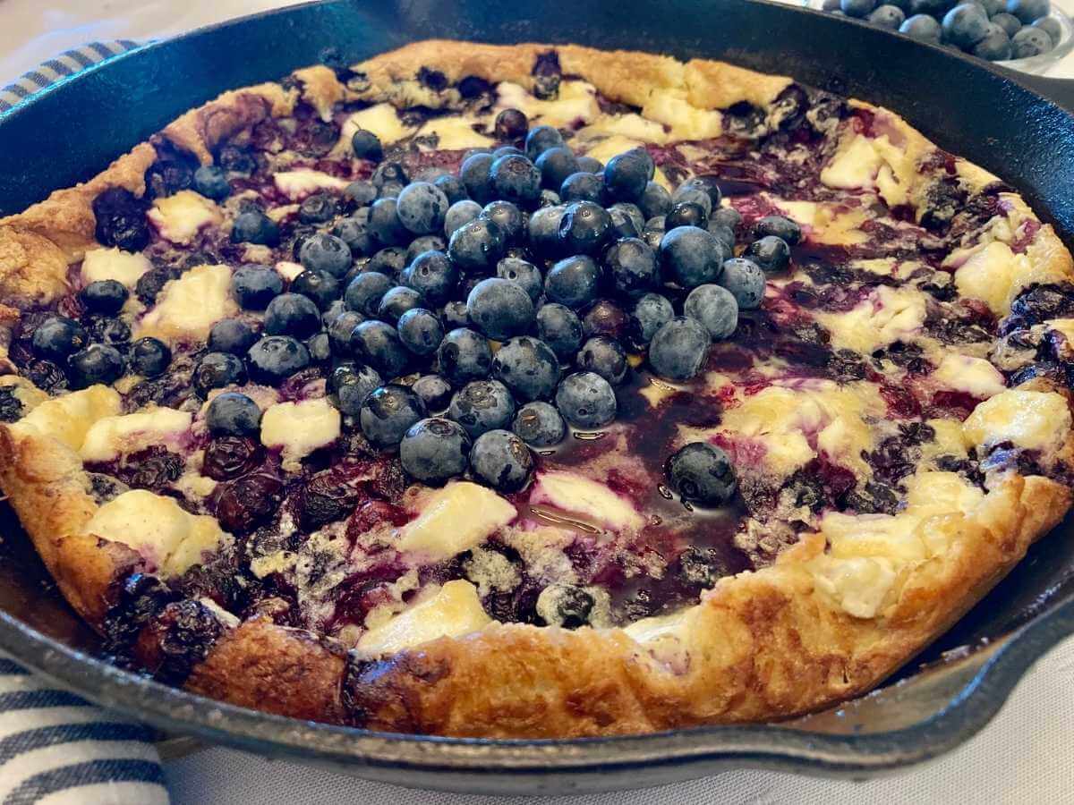 Skillet with blueberry cheesecake German pancake with blueberries on top.