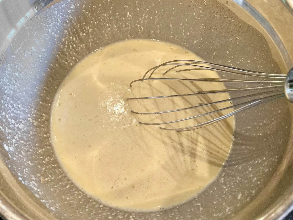 Whisking German pancake batter in a bowl.