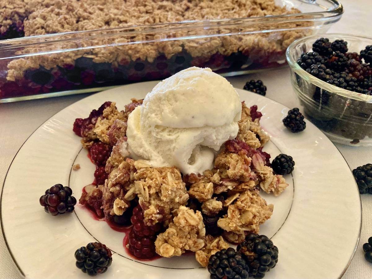 Gluten-free blackberry crisp with ice cream on a plate.