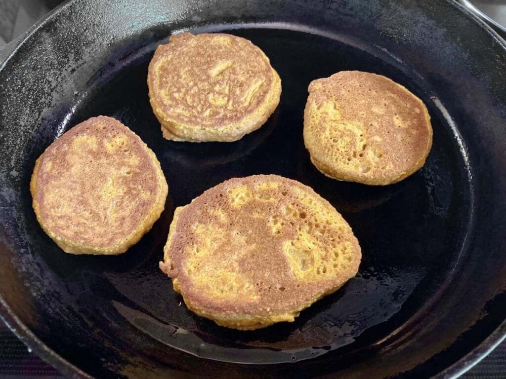 Frying gluten-free pumpkin pancakes in a cast iron skillet.
