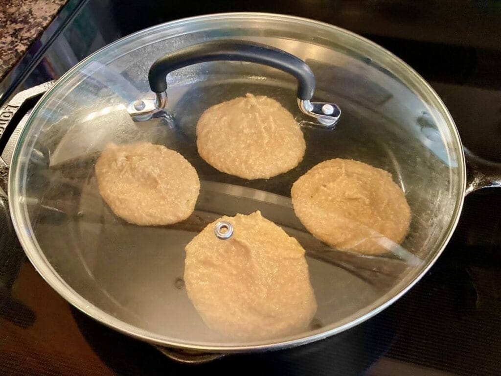 Frying pumpkin pancakes in a skillet with a lid.
