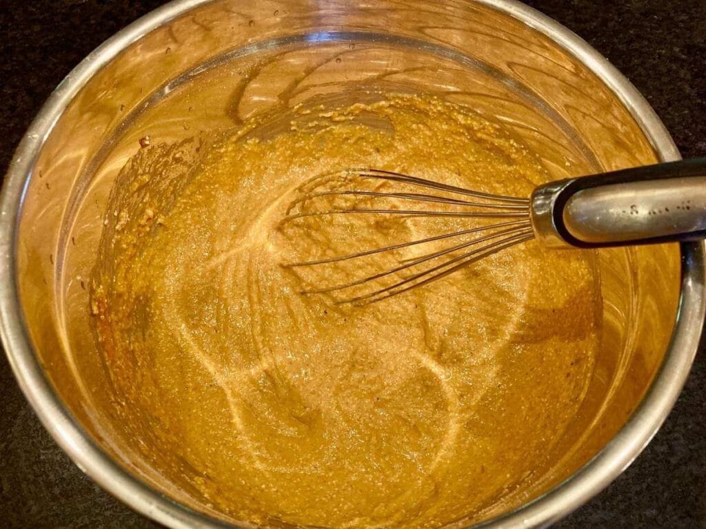 Whisking gluten-free pumpkin pancake batter in a bowl.