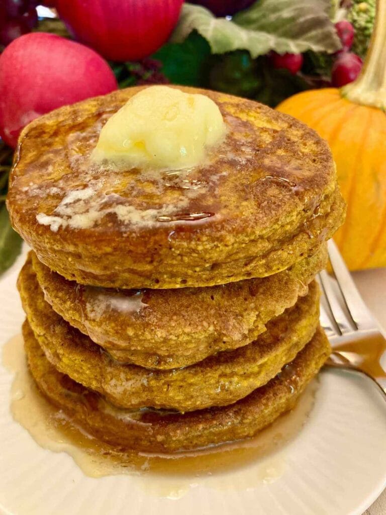 Stack of gluten-free pumpkin pancakes on a plate with a fork.