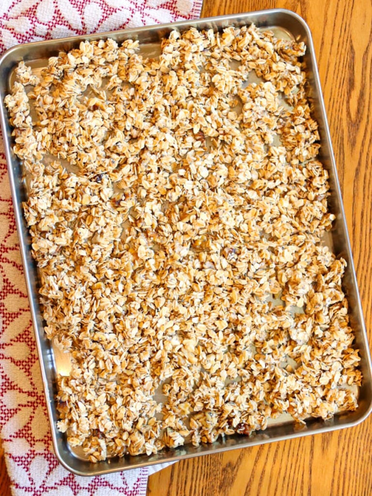 Unbaked granola on a cookie sheet on a wood table.